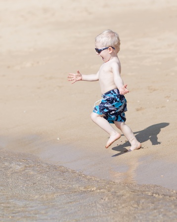 adorable little boy running at the beachの写真素材