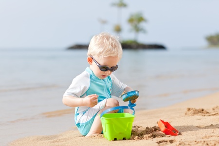 adorable toddler playing in sand on a tropical beachの写真素材