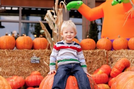 smiling caucasian toddler sitting on the huge pumpkinの写真素材
