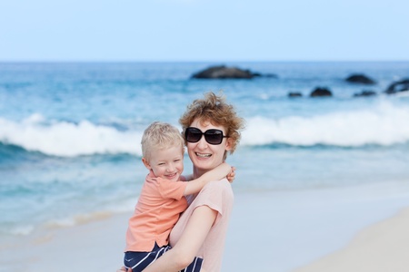 laughing mother holding her son at the beachの写真素材