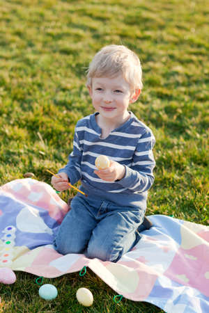 adorable smiling little child coloring easter eggsの写真素材
