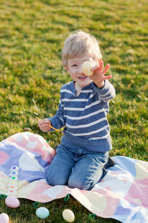 adorable smiling little child coloring easter eggsの写真素材