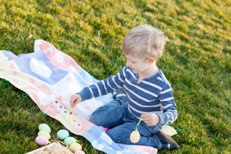 adorable smiling little child coloring easter eggsの写真素材