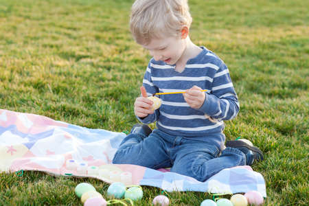 adorable smiling little child coloring easter eggsの写真素材