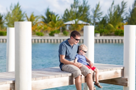 father and his son sitting together at the moorageの写真素材