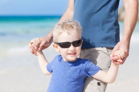 handsome little boy with his father at the tropical beachの写真素材