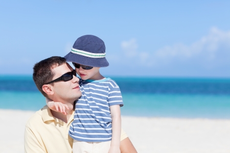 young handsome father and his son hugging at the caribbean tropical beachの写真素材