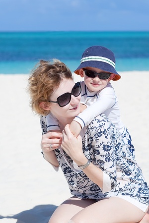 happy smiling kid hugging with his mother at the beachの写真素材