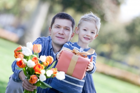 handsome young man and child offering a gift and flowersの写真素材