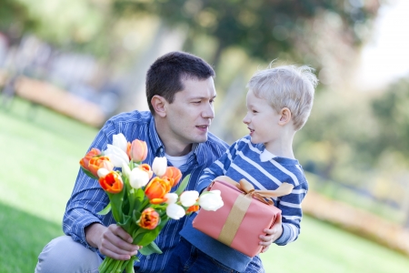 handsome young man and child offering a gift and flowersの写真素材
