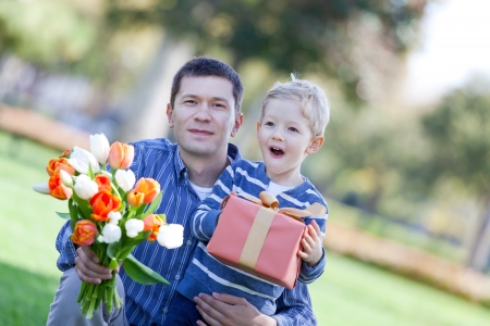 handsome young man and child offering a gift and flowersの写真素材