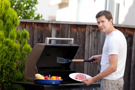 young handsome man ready for grilling meat and vegetables at his house backyardの写真素材