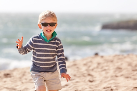 handsome little boy running at the beach; adorable laughing boy enjoying summer in californiaの写真素材