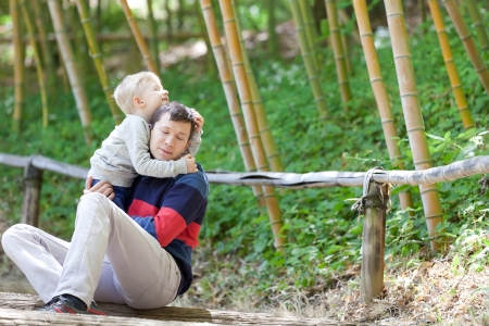 happy family of two enjoying time together outdoors; cute little boy hugging his fatherの写真素材