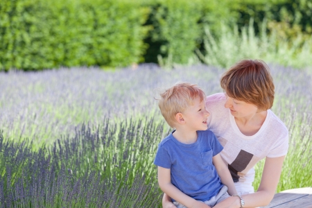 young beautiful mother and her adorable son spending time together at blooming lavender fieldsの写真素材