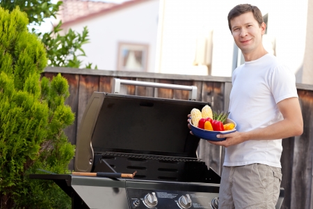 smiling handsome man ready for grilling vegetablesの写真素材