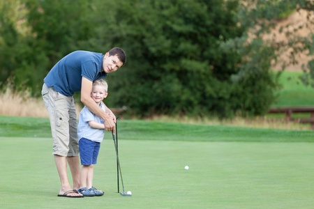young father and his happy smiling son playing golf togetherの写真素材