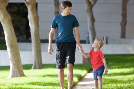 handsome father and his cute smiling son walking together outsideの写真素材