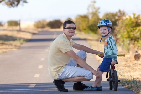 smiling cute boy with a balance bike spending fun time together with his handsome fatherの写真素材