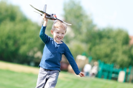 smiling excited boy playing a toy plane in the parkの写真素材