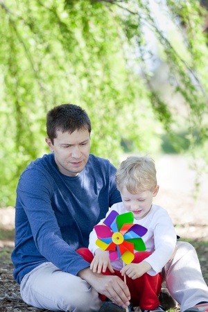 happy father and his cute son with a pinwheel spending time together at the parkの写真素材