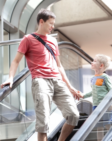 happy smiling father and his excited son at the airport escalatorの写真素材