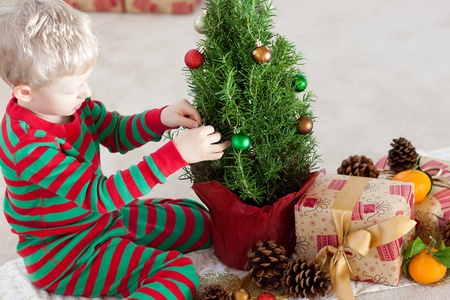 cute caucasian boy decorating a christmas tree at winter timeの写真素材