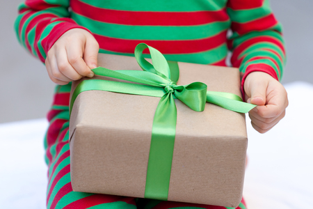 little child unwrapping his christmas present, close-upの写真素材
