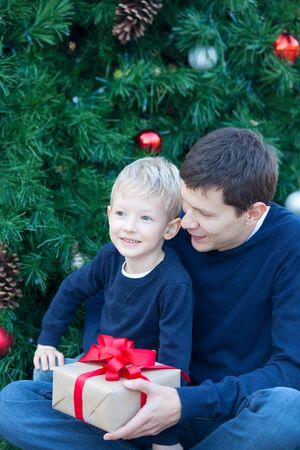 cheerful smiling boy and his father with gift box at christmas timeの写真素材