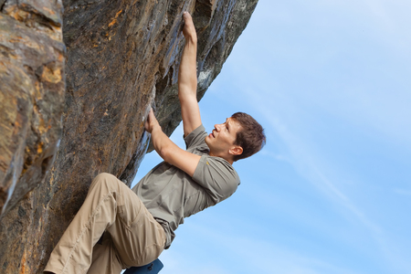 young healthy man rock climbing or bouldering outdoorsの写真素材