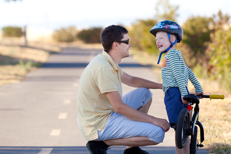happy smiling father and his cheerful son with balance bike being sillyの写真素材