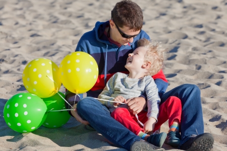happy cheerful family of two spending fun time with balloons at the beachの写真素材