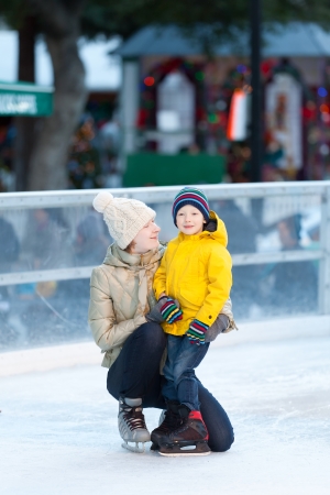 happy smiling mother and her cute cheerful son ice skating together at winterの写真素材