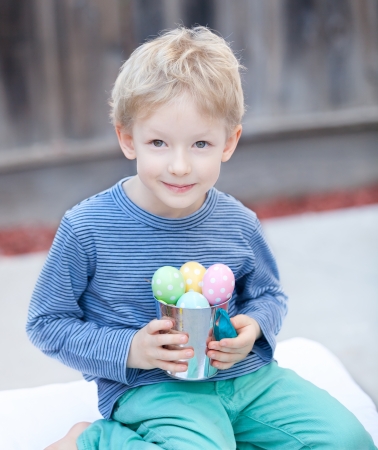 cute positive boy with easter colorful eggs in the bucket at springの写真素材