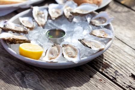 fresh raw oysters served with lemon and sauce at the plate with iceの写真素材