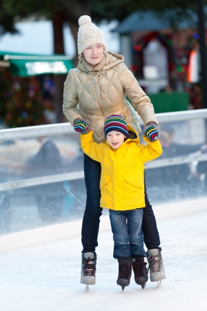 happy smiling mother and her cute cheerful son ice skating together at winterの写真素材