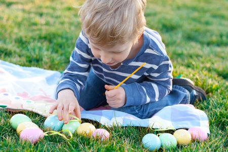 happy positive boy coloring easter eggsの写真素材