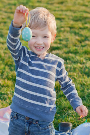 happy smiling boy coloring and showing easter eggの写真素材