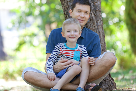 happy family of father and son sitting in the parkの写真素材