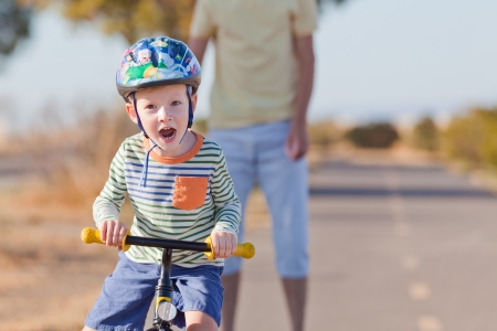 cheerful little boy in helmet at balance bikeの写真素材