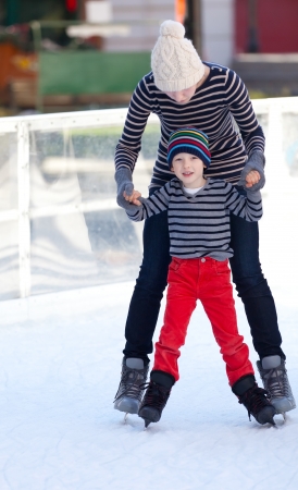cheerful mother and her little son enjoying ice skating together at winterの写真素材
