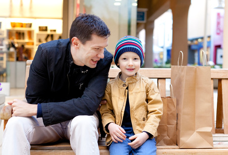 family of two sitting at the bench at shopping plazaの写真素材