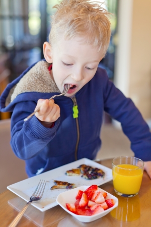 cheerful little boy eating breakfastの写真素材
