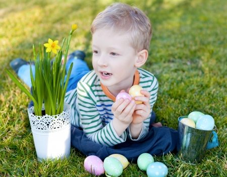 cheerful positive little boy holding colorful eggs at easter timeの写真素材