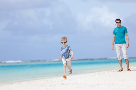 little boy running at the beach, his father waiting, tropical vacation togetherの写真素材