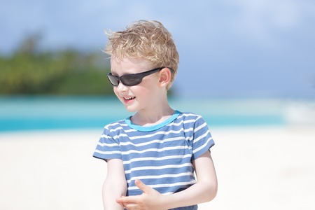 portrait of smiling little boy standing at picture perfect beach