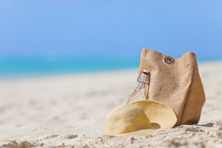 straw hat, beach bag and bottle of water at the beach, summer vacation conceptの写真素材