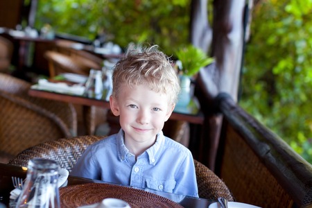 little cute boy waiting for his breakfast at the hotelの写真素材