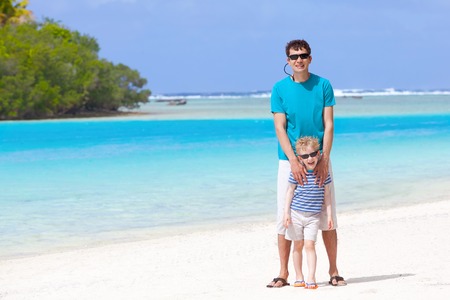 handsome young father and his little smiling son at the perfect beachの写真素材