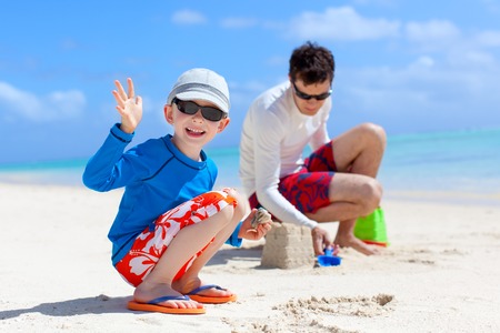cheerful family building sand castle at the beachの写真素材